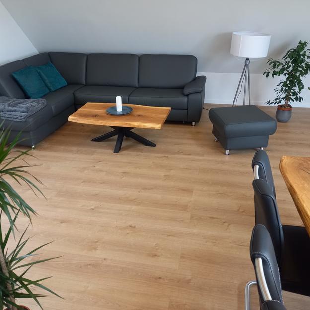Wohnzimmer mit Blick auf schwarze Couch und Holz-Couchtisch