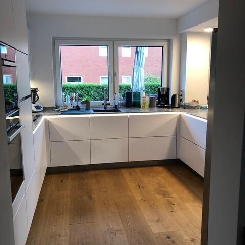 Moderne Küche mit weißen Fronten und Holzboden