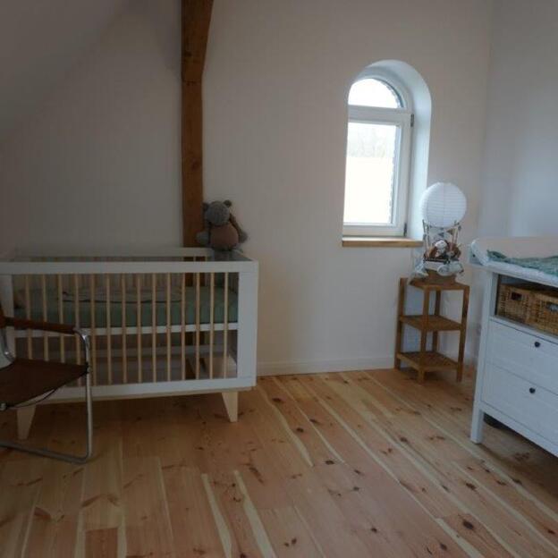 Kinderzimmer mit weißen Möbeln unter Dachschräge und mit Holzboden