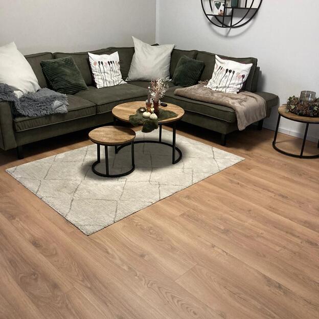 Dunkle Couch vor hellem Teppich und Couchtisch aus Holz