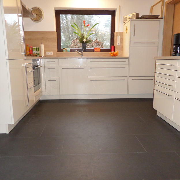 Küche mit weißen Fronten auf dunklen Fliesen