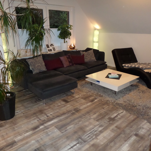 Dunkle Wohnzimmercouch und weißer Couchtisch auf Holzboden