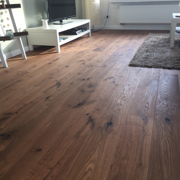 Holzboden in Nahaufnahme mit Wohnzimmermöbeln im Hintergrund