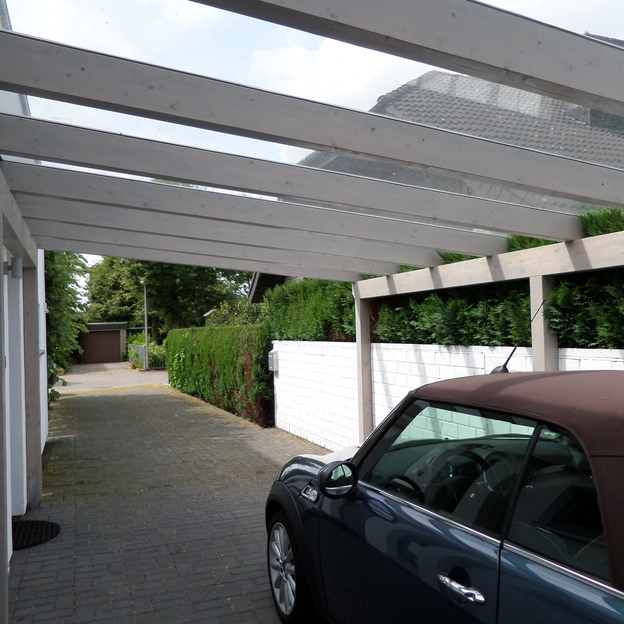 Schwarzes Auto unter einem Carport aus Holzbalken