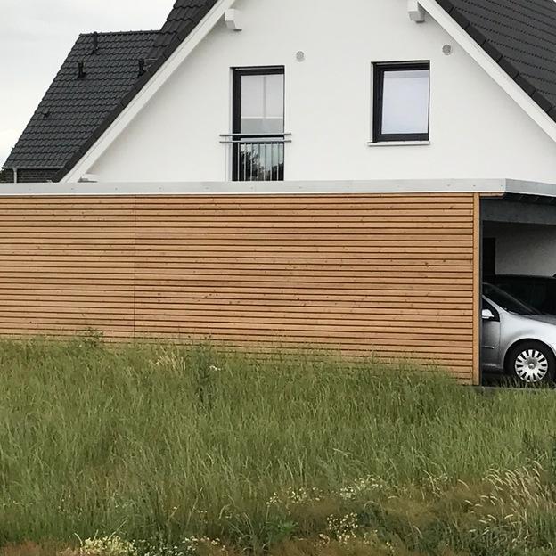 Holzverkleidetes Carport mit silbernem und schwarzem Auto