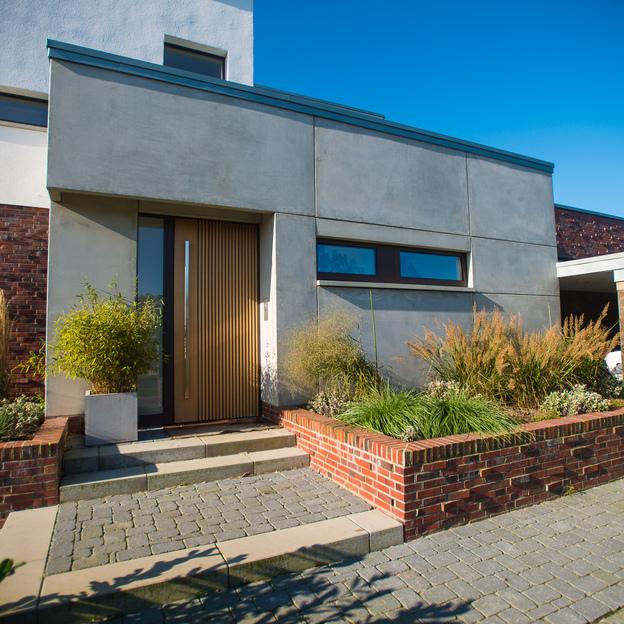 Zeitgenössische Architektur mit maßgefertigten Fenstern, Beton und Ziegeloberflächen, umgeben von angelegten Gärten.