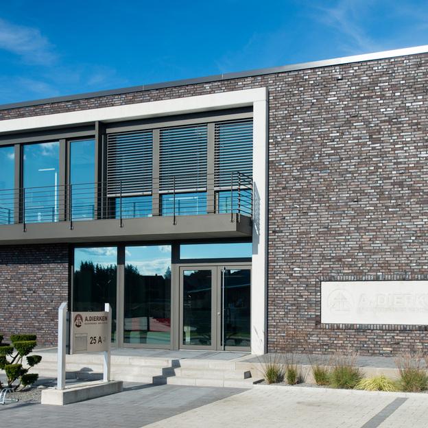 Zwei-stöckiges Geschäftsgebäude mit einer Klinkerfassade und maßgefertigten Fenstern sowie einer Glasfront im Erdgeschoss.