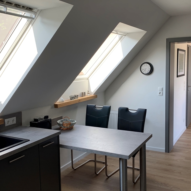 Helle Dachgeschossküche mit moderner Einrichtung und maßgeschneiderten Dachfenstern, die viel Tageslicht hereinlassen.