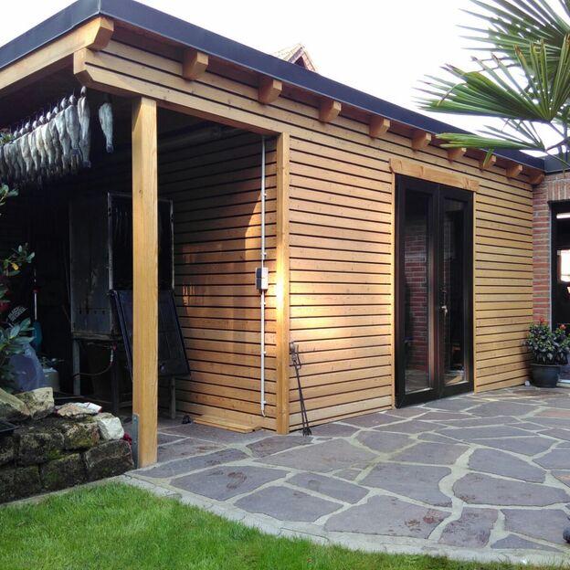 Modernes Gartenhaus mit Holzverschalung, Doppeltür und seitlicher Nische mit Räucherofen und aufgehängtem Räucherfisch.