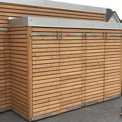 Seitlicher Anbau mit Holzverkleidung und Klappen zur Mülltonnenlagerung, angebaut an ein modernes Gartenhaus.