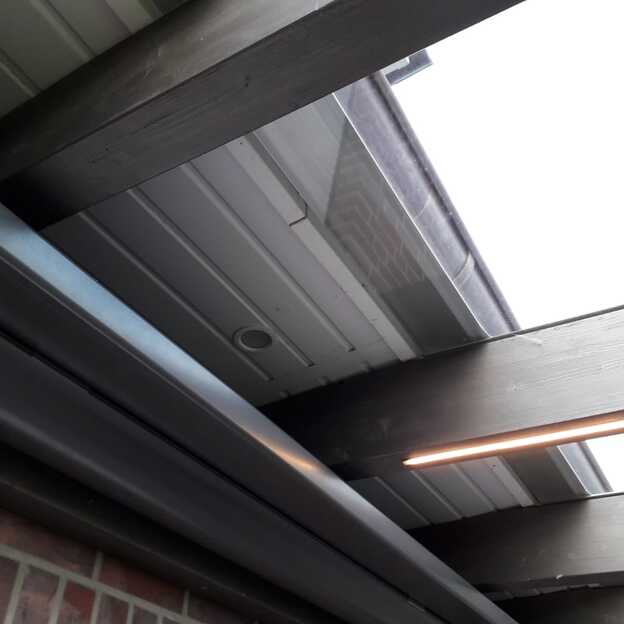 Nahaufnahme der Terrassenüberdachung mit Glasdach, LED-Beleuchtung und Wandanschluss unter der Dachrinne.