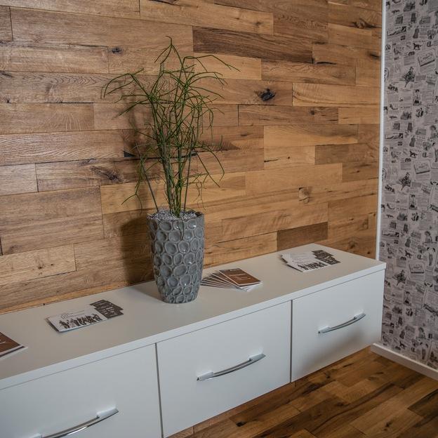 Ein weißes Sideboard vor einer verkleideten Holzwand