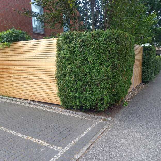 Brauner Holzzaun in einer Auffahrt