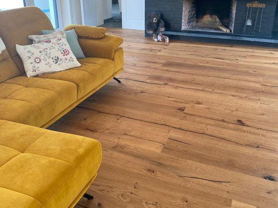 Wohnzimmer mit dunklem Kamin, gelbem Sofa und Holzboden in warmem Farbton, gemütlich und modern eingerichtet.