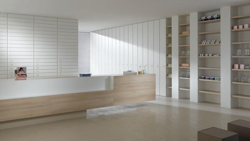 Impressionen einer Apothekeneinrichtung mit hellen Holzmöbeln und geräumigem Regalsystem, sowie aufgeräumten Empfang.